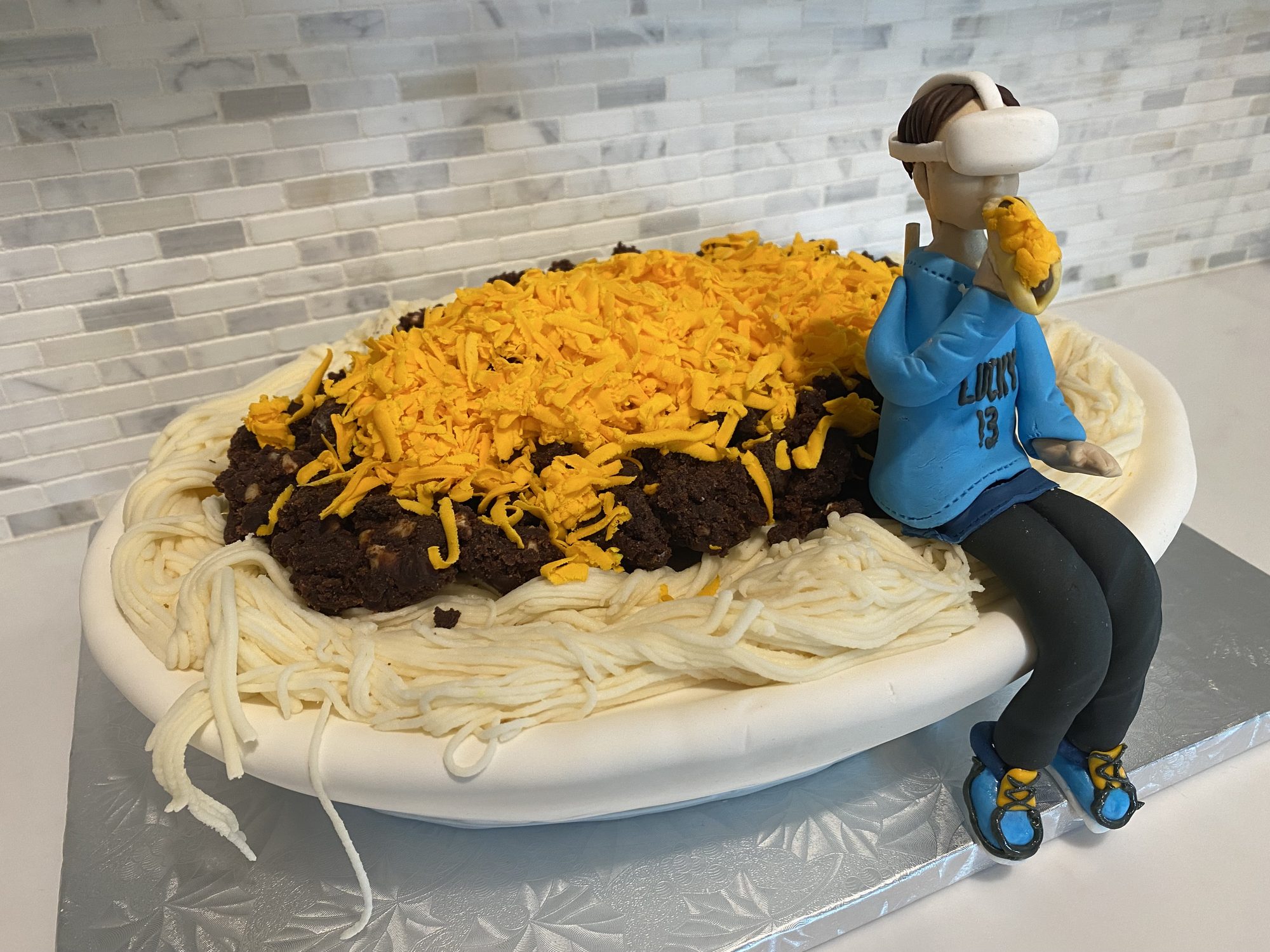 Sculpted bowl of chili spaghetti cake with a seated figure